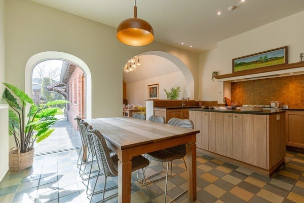 Sunlit kitchen and dining area with a wooden table and modern island.