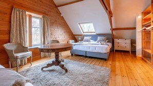 Ein gemütliches Schlafzimmer mit schrägverlaufender Decke, einem Bett, einer Kommode, einem Stuhl und einem Tisch.