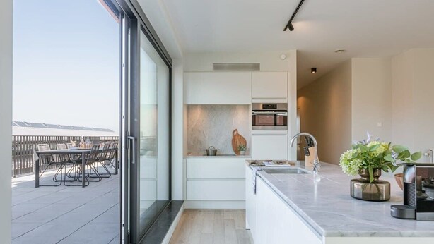 A modern kitchen with a large window, a dining area with outdoor seating, and a view of the cityscape. - Bright 2BR apartment w/ balcony & private entrance (Gent)