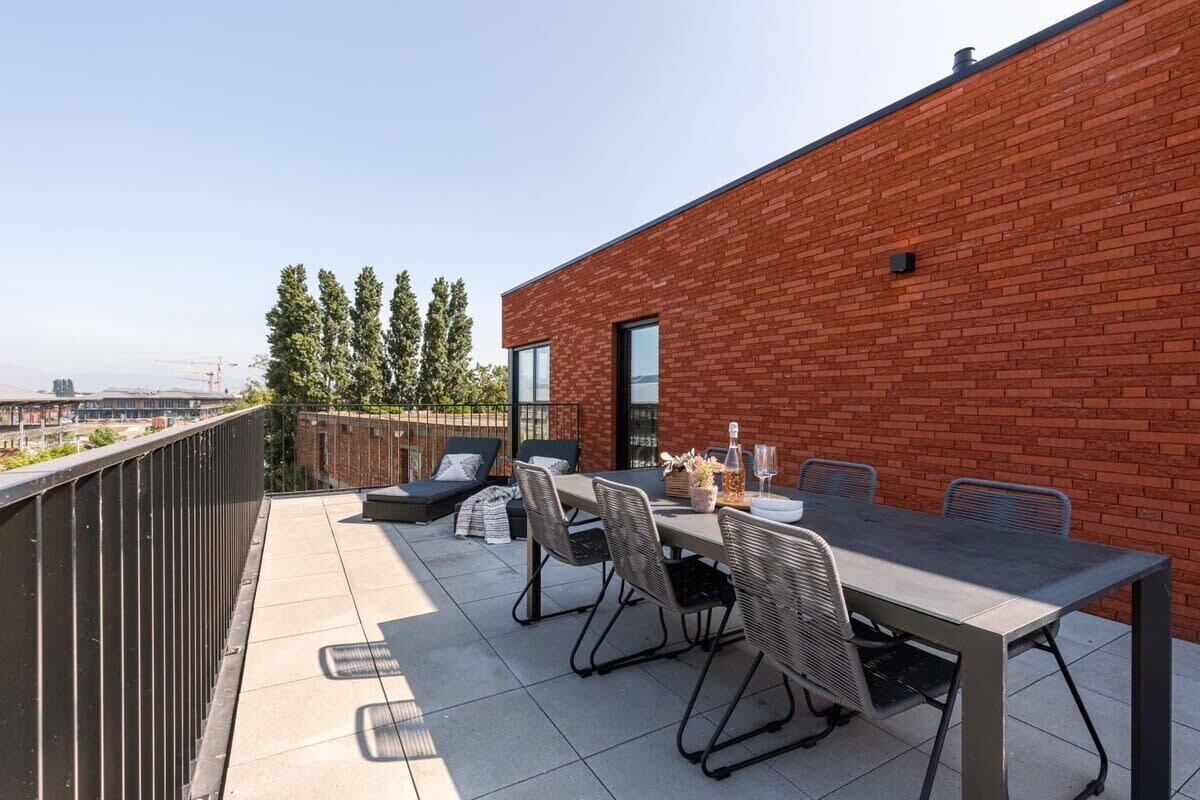 Terraço no telhado com mesa, cadeiras e vista para a paisagem urbana.