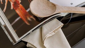 Un livre de recettes dont la couverture est ornée d’une image de homard, posé sur un plan de travail de cuisine.