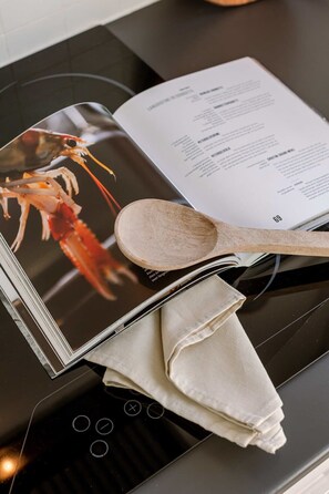 A cookbook with a lobster image on the cover, placed on a kitchen counter. - Beachfront Apt w/ Gear & Free Parking, De Haan (De Haan)