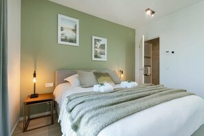 A bedroom with a bed, bedside lamps, and two framed pictures on the wall. - 1BR unit w/ parking & elevator (Oostende)