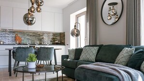 Un soggiorno moderno con un divano verde, un tavolino rotondo e un'area da pranzo con sedie e un tavolo con piano in vetro.