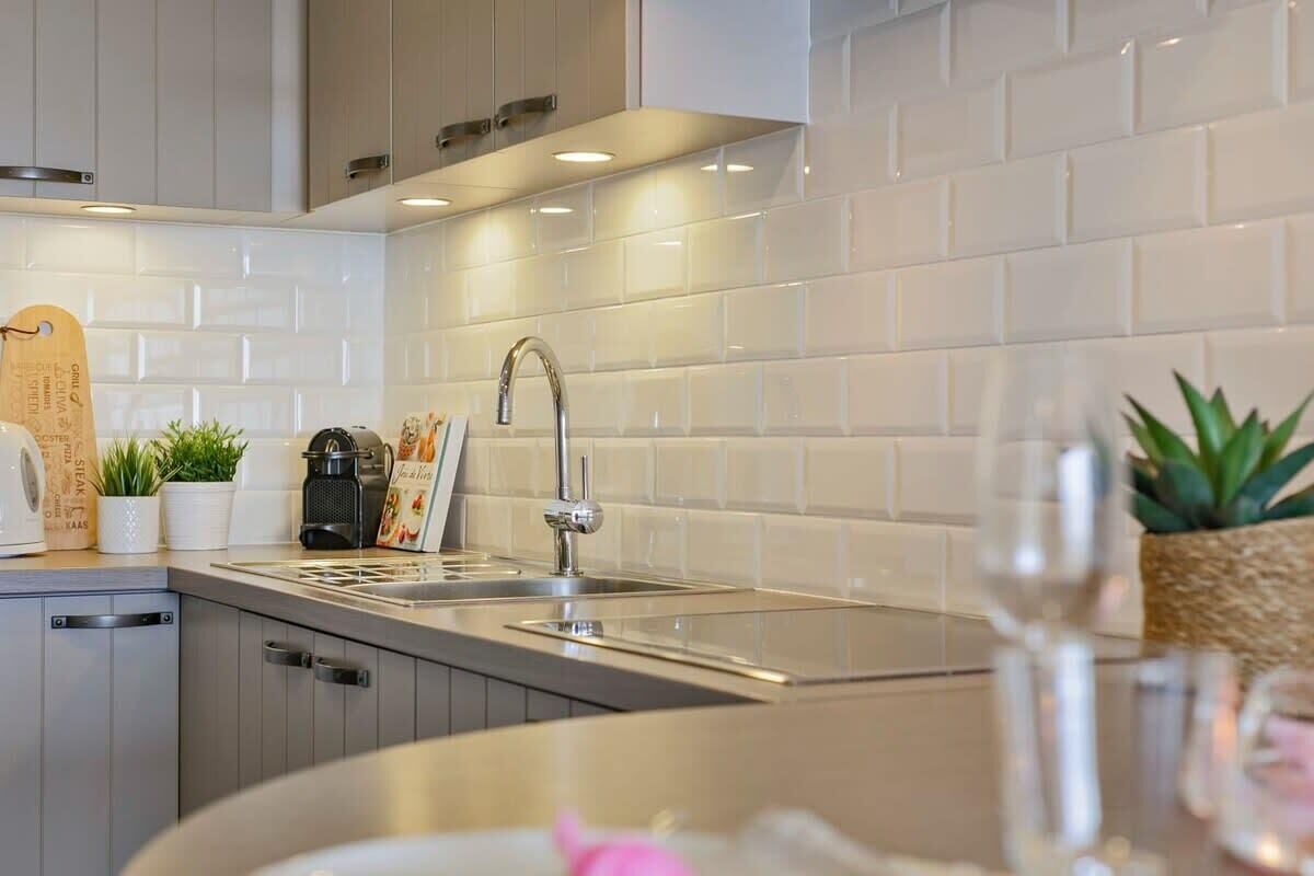 Una cocina moderna con un lavamanos de acero inoxidable, una cafetera y una planta en maceta.