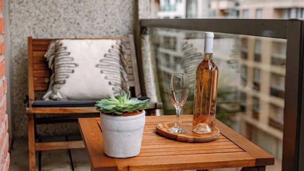 A balcony with a wooden table, a potted plant, a bottle, and a glass. - Beachfront Gem w/ Balcony & Family Friendly in (Knokke-Heist)
