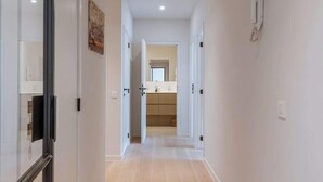 A hallway with a wooden floor, white walls, and a bathroom visible in the distance. - Beachfront Gem w/ Balcony & Family Friendly in (Knokke-Heist)