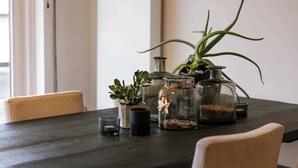 A dining table with various glass containers, a potted plant, and a candle. - Beachfront Gem w/ Balcony & Family Friendly in (Knokke-Heist)