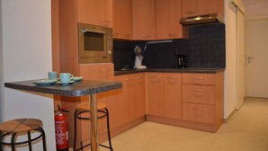 A compact kitchen with wooden cabinets, a microwave, a coffee maker, and a small dining area with stools. - Beachfront Apartment w/ Patio, Pet-Friendly, in (Oostende)