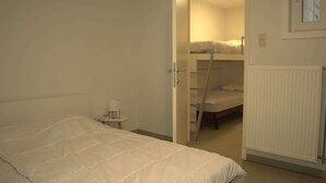 A bedroom with a bunk bed, a small bedside table, and a radiator. - Beachfront Apartment w/ Patio, Pet-Friendly, in (Oostende)