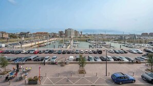 A marina with boats, a parking lot with cars, and buildings in the background. - Waterfront studio w/ private entrance (Blankenberge)