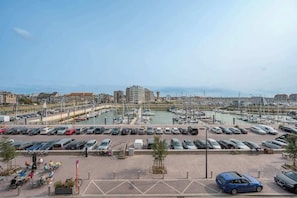 Ein Yachthafen mit Booten, ein Parkplatz mit Autos und Gebäude im Hintergrund.