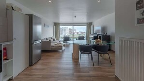 A modern apartment with a dining area, kitchen, and a large window offering a city view. - Waterfront studio w/ private entrance (Blankenberge)