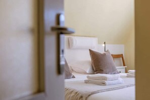 Ein Hotelzimmer mit Bett, Kissen, Nachttisch und Lampe.