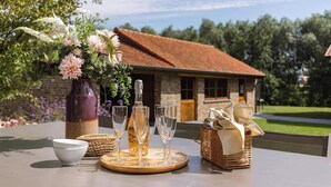 A table set with a vase of flowers, a bottle, glasses, and a basket with bread.