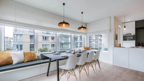 A modern kitchen with a dining area, large windows, and a view of the city. - Casiola coastal stay - parking & terrace (Knokke-Heist)
