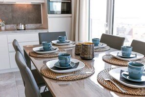 Ein Esstisch, gedeckt mit blauen Tassen und Tellern, einer gewebten Tischmatte und einer dekorativen Vase.