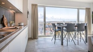 Et moderne køkken med spiseplads, store vinduer og udsigt til byen.