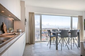 Eine moderne Küche mit Essbereich, großen Fenstern und Blick auf die Stadt.