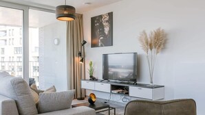 En moderne stue med sofa, sofabord, fjernsyn og dekorative planter.