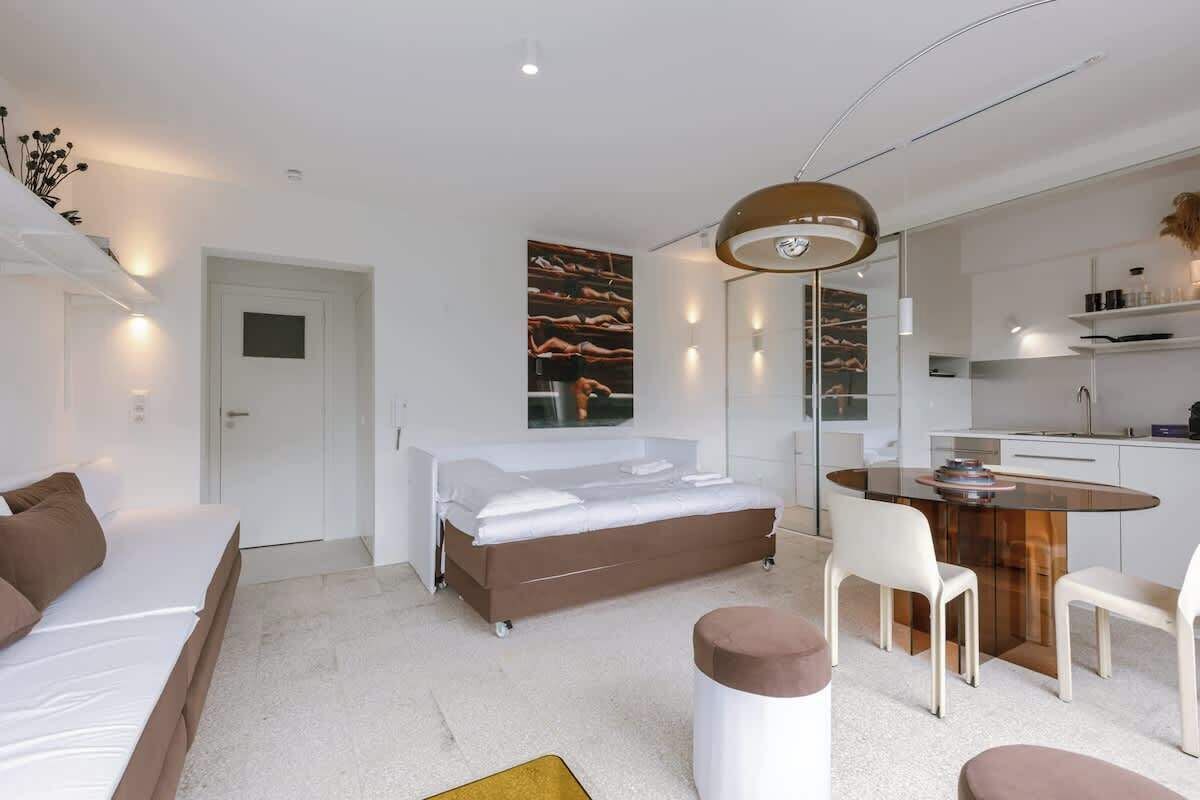 Habitació d'hotel moderna amb un llit, una taula de menjador i cadires.