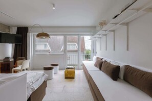 Una habitación de hotel moderna con cama, sofá, escritorio y un amplio ventanal.