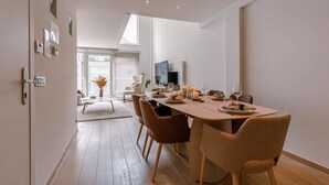 Een moderne eetruimte met een lange tafel, stoelen en een televisie.