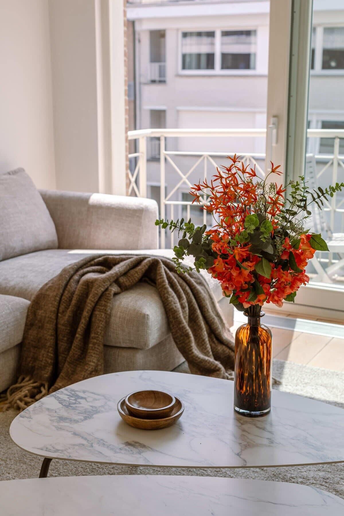 Ein Wohnzimmer mit einer Couch, einem Couchtisch und einer Vase mit Blumen.