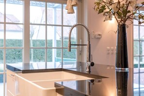Une salle de bain moderne avec une grande fenêtre, un vase noir orné de fleurs et un robinet chromé.
