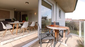 En balkon med spisebord og stole, en skydedør samt udsigt ud