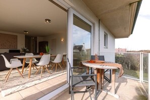 A balcony with a dining table and chairs, a sliding glass door, and a view of the outside.