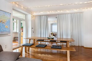 A modern living room with a wooden dining table, cushioned benches, a globe map, and a string of lights. - Apartment in Historic Villa with Wi-Fi (Stockach)
