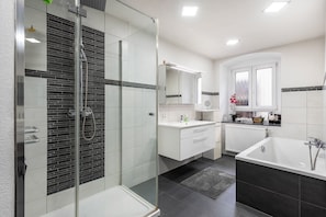 A modern bathroom with a glass-enclosed shower, a freestanding bathtub, and a vanity with a mirror. - Apartment in Historic Villa with Wi-Fi (Stockach)