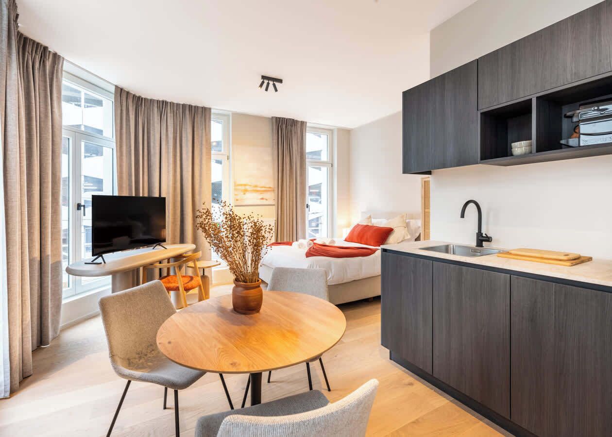 Een moderne hotelkamer met een zithoek, een televisie, een bank en een kitchenette.