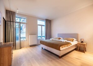 A bedroom with a large bed, a bedside table with a lamp, a window with curtains, and a view of the outside. - Pet-friendly Ghent retreat w/ terrace (Gent)
