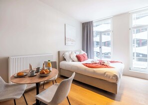 A modern hotel room with a bed, a dining table with breakfast, and large windows. - Bright studio retreat w/ workspace (Gent)