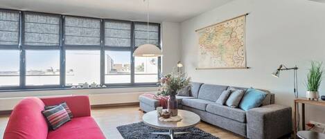 A modern living room with a red sofa, grey sofa, and a coffee table with decorative items.