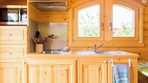 A wooden kitchen with a microwave, stove, sink, and cabinets.