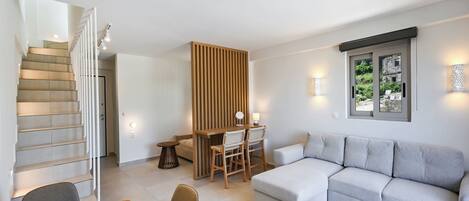 A modern living room with a staircase, a dining area, and a seating area with a view of the outdoors.