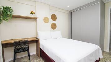 Un dormitorio con una cama, un escritorio y una silla.