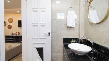 A bathroom with a white door, a sink, a mirror, and towels on the wall.
