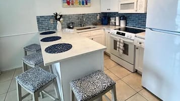 Eine Küche mit Kochinsel, Barhocker, Mikrowelle, Backofen und Kühlschrank.