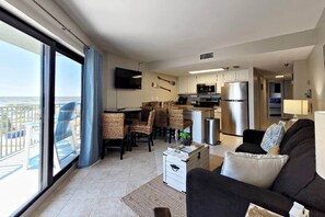 A modern living room with a dining area, kitchen, and a balcony with a view. - SunGlow 807 (Daytona Beach Shores)