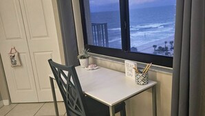 Ett rum med utsikt över havet, ett bord med en växt och en skylt, och en stol.