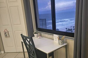 A room with a view of the ocean, a table with a plant and a sign, and a chair. - SunGlow 807 (Daytona Beach Shores)