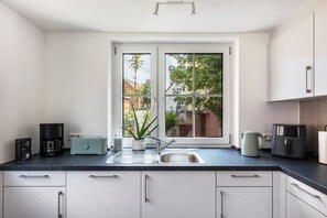 A modern kitchen with a large window, a coffee machine, a toaster, and a kettle. - Apartment at the Fountain (Schrozberg)