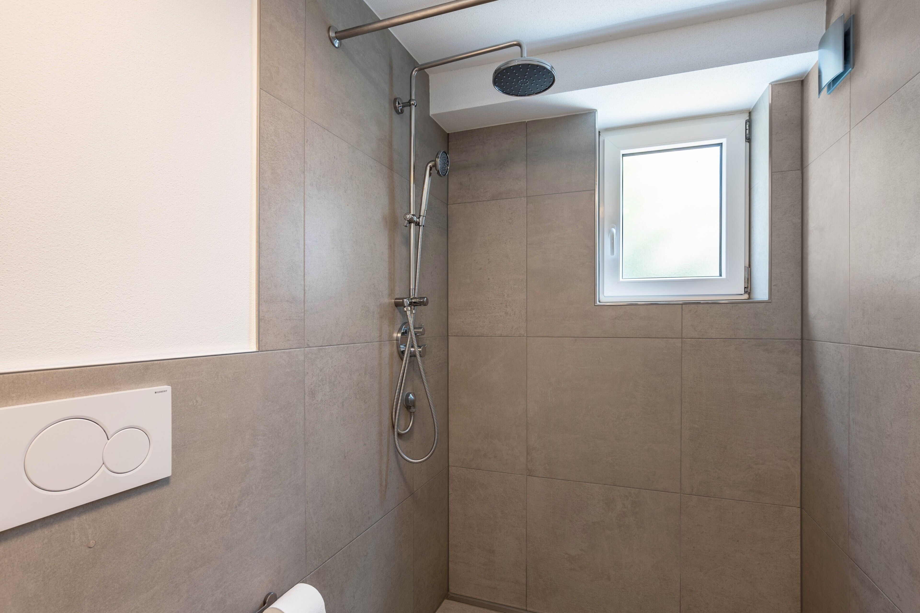 Une douche équipée d’un pommeau de douche à main, d’un autre pommeau de douche à main et d’un pommeau de douche fixé au mur.