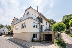 A two-story residential building with a balcony, a stone entrance, and a paved driveway. - Apartment at the Fountain (Schrozberg)