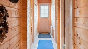A wooden interior hallway with a blue mat on the floor, a window with blinds, and a hanging light fixture. - 4 Star Holiday Home in Stege (Stege)