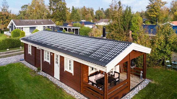 A single-story wooden house with a covered porch, a small deck, and a gravel driveway. - 4 Star Holiday Home in Stege (Stege)